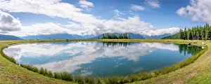 View of reflection of mountains and clouds in Plettsaukopf Reservoir on a sunny day, Bruckberg, Salzburg, Austria, Europe