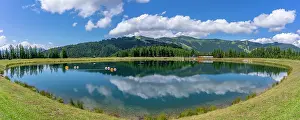View of reflection of mountains and clouds in Plettsaukopf Reservoir on a sunny day, Bruckberg, Salzburg, Austria, Europe