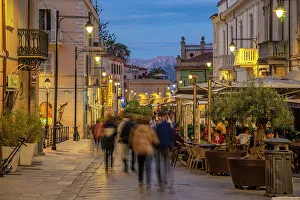 Adults Prints: View of restaurants on Corso Umberto I at dusk in Olbia