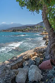 Limenas Prints: View of rocky coastline along Limenas Chersonisou in Crete with clear water and distant mountains in Greece