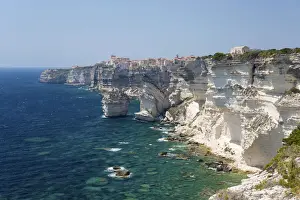 Corsica Prints: View over rocky cove along rugged limestone cliffs to the distant citadel