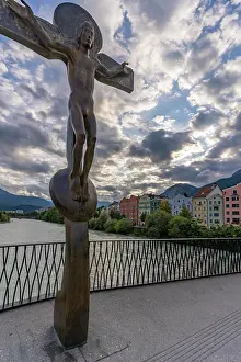 Aesthetics Prints: View of Rudi Wach Kreuz sculpture on a bridge with colorful buildings at sunset in Innsbruck