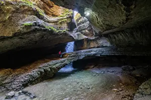 Waterfall Prints: View of Saltinskiy Underground Waterfall in Dagestan with a person standing near the water source