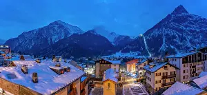 View of snow covered rooftops with mountainous background at dusk, Courmayeur, Aosta Valley, Italy