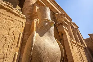 Symbolism Prints: View of statue of Horus the falcon outside the doorway to the sandstone Temple of Horus at Edfu