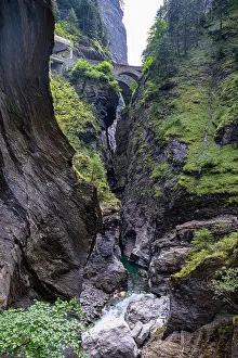 Flowing Prints: View of steep cliffs with water flowing in a narrow gorge in Switzerland under a cloudy sky