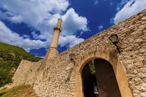 Tall Prints: View of stone fortress walls and mosque minaret under blue sky in Budapest
