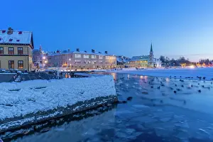 Stillness Prints: View of swans and ducks with Lutheran Free Church in background in the city centre of Reykjavik at dusk in winter