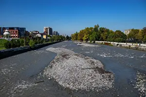 Flowing Prints: View of the Terek River with rocky banks and buildings in the background in Vladikavkaz