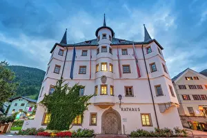 Rathaus Prints: View of Town Hall in Zell am See at dusk with lights shining from windows and flags displayed