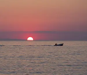 Cefalu Prints: View across the Tyrrhenian Sea at sunrise, small boat crossing Calura Bay, Cefalu