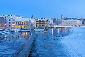 Cozy Prints: View of waterfront buildings and city skyline in background in the city centre of Reykjavik at dusk in winter