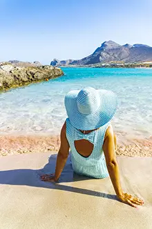 40 45 Years Prints: Back view of woman contemplating the sea sitting on pink sand of Falassarna beach