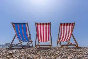 View of Worthing Pier and colourful deckchairs on Worthing Beach, Worthing, West Sussex View of Worthing Pier and colourful deckchairs on Worthing Beach, Worthing, West Sussex