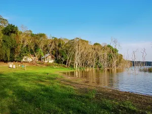 Waterscape Prints: View of Yaxha Lake with trees and a building adjacent to the water in Guatemala