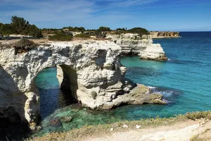 Route Prints: Views of Faraglioni in Salento with clear blue water and rocky cliffs on a sunny day in Italy