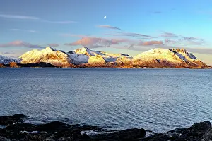 Moon Prints: Views of Vestvagoy Island with snow-covered peaks and clear sky from Henningsvaer in Lofoten Islands