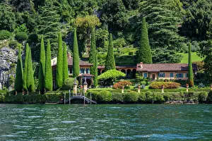 Gardens Prints: Villa La Cassinella shows lush greenery and gardens along the shoreline of Lake Como in Italy with cypress trees