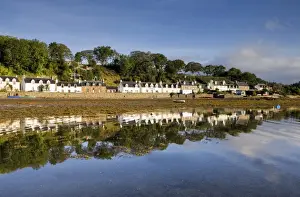 Village of Plockton bathed in early morning light and reflecting in calm sea at low tide