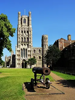 Lawn Prints: Visit to Ely Cathedral with a historic cannon in the foreground under a clear blue sky in Ely Cambridgeshire