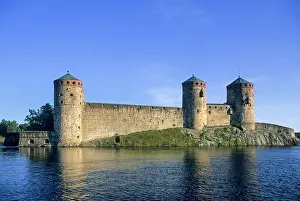 Finland Prints: Visit Olavinlinna medieval castle in Savonlinna by the lake in Finland surrounded by clear blue skies and water