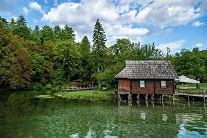 Fresh Prints: Visit to Plitvice Lakes National Park features wooden house by the water under blue sky in Croatia
