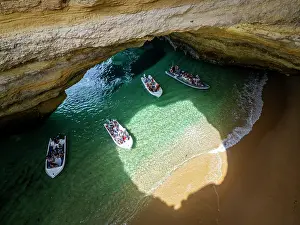 Route Prints: Visitors explore Algar de Benagil cave in Portugal by boat during a sunny day
