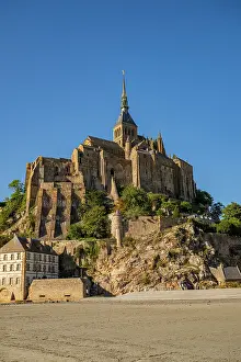 Visitors Prints: Visitors explore Mont St. Michel rising above the landscape in France during a clear day