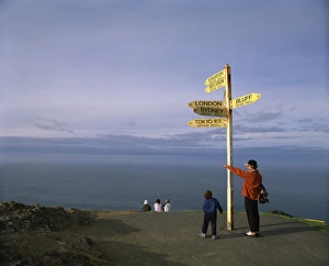 Northland Prints: Visitors by the sign at Cape Reinga on the coast of Northland