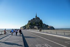 Streets Prints: Visitors walk towards Mont St. Michel on a sunny day in France enjoying the view of the historic site