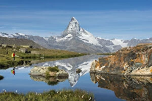 Contemplation Gallery: A walker hiking in the Alps takes in the view of the Matterhorn reflected in Stellisee