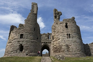 Walkers arrive at historic Dunstanburgh Castle, Northumberland, England, United Kingdom