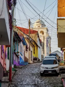 Small Prints: Walking down a cobblestone street with vibrant houses and a church in the background in Flores Island