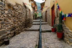 Sights Prints: Walking through a stone pathway in Ollantaytambo with colorful decorations during a sunny day in Peru