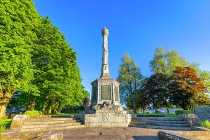 Columns Prints: Wallace Birthplace Monument stands tall in Elderslie surrounded by trees under a clear blue sky in Scotland