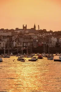 Channel Prints: Warm evening light shines over the skyline of St Peter Port and church towers in Guernsey Channel Islands