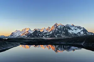 Awe Inspiring Prints: Warm morning lights on snowy mountains reflected in a pool by the fjord