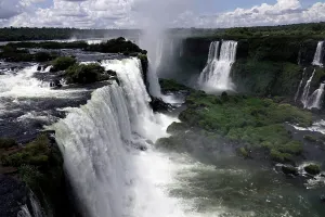 Large Prints: Water flows from Iguazu Falls in Brazil with clouds and greenery in view during the day