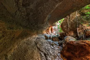 Trail Prints: Water flows under a natural stone arch in Barranco de Luna gorge in Granada
