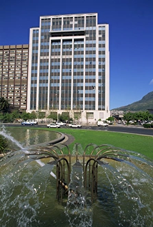 Cape Province Prints: Water fountain on round-a-bout with an office building behind