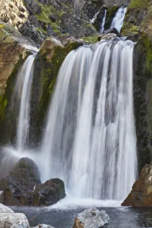 Flowing Gallery: A waterfall cascades down a gorge cut into coastal cliffs, at Spekes Mill Mouth