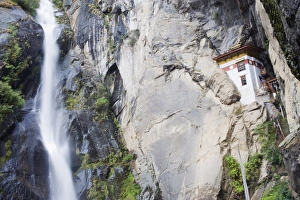 A waterfall flowing past a temple built into the side of a cliff, Tigers Nest A waterfall flowing past a temple built into the side of a cliff, Tigers Nest