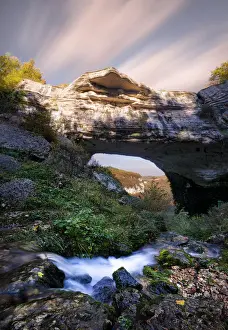 Waterfall flowing below Veja bridge, a huge natural arch in Lessinia, Veneto, Italy