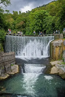 Flowing Prints: Waterfall flows over artificial rocks with people enjoying the view near New Athon