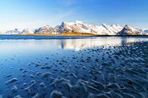 Nordland County Gallery: Waves of the cold sea crashing on the beach with snowy mountains on background, Fredvang, Nordland