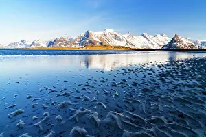 Lofoten Islands Prints: Waves of the cold sea crashing on the beach with snowy mountains on background