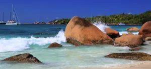 Recreational Prints: Waves crash against large rocks on the shore of Anse Georgette during a sunny day in Seychelles