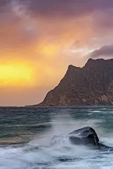 Breeze Prints: Waves crash against rocks under sunset skies at Uttakleiv