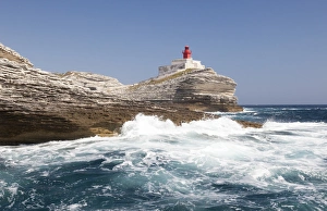 Waves of the turquoise sea crashing on the granite white cliffs and lighthouse, Lavezzi Islands Waves of the turquoise sea crashing on the granite white cliffs and lighthouse, Lavezzi Islands