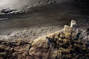 Zealand Prints: Weathered sandstone forms and dark sand contrast at a coastline in New Zealand